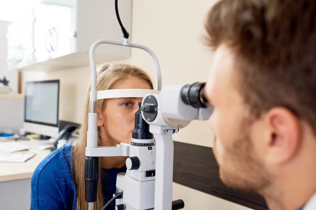 Syntest på mottagning, undersökningsansvarig och patient sitter vid ögontestmaskin