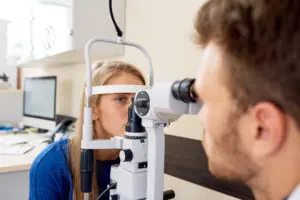 Syntest på mottagning, undersökningsansvarig och patient sitter vid ögontestmaskin